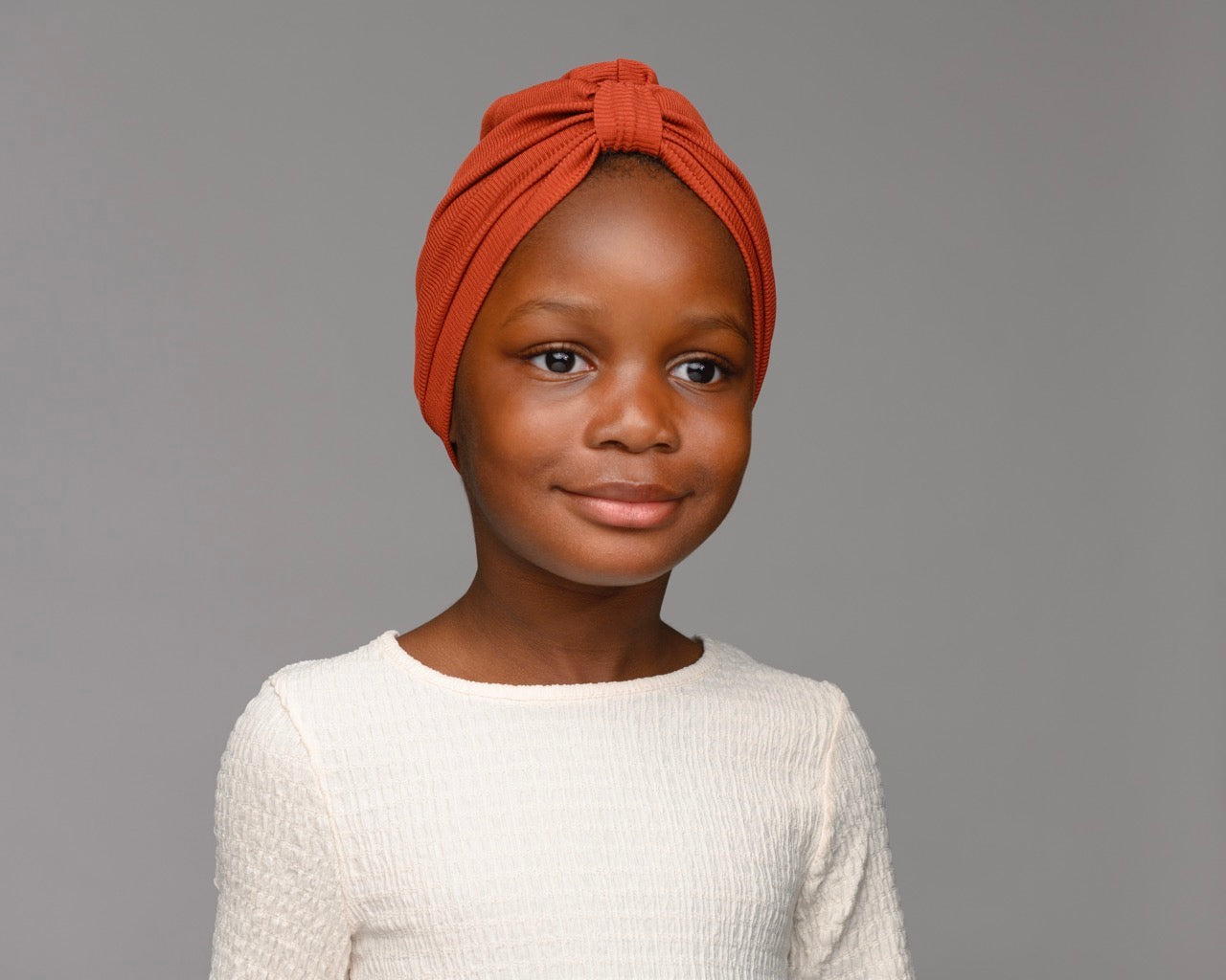 Child model wearing auburn turban