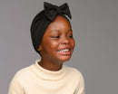 Child model wearing black turban with a bow