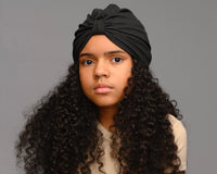 Child model with long curly hair wearing black turban