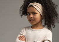 Child female with tied up curly hair wearing a stone colour bowless headband