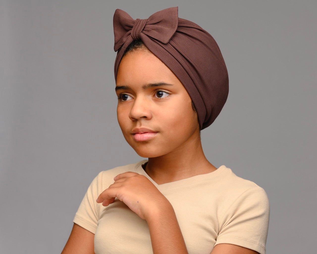 Child model posing wearing chocolate t- brown turban with a bow